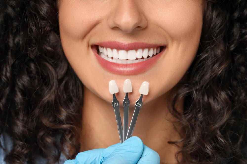 woman comparing natural tooth color to custom veneers